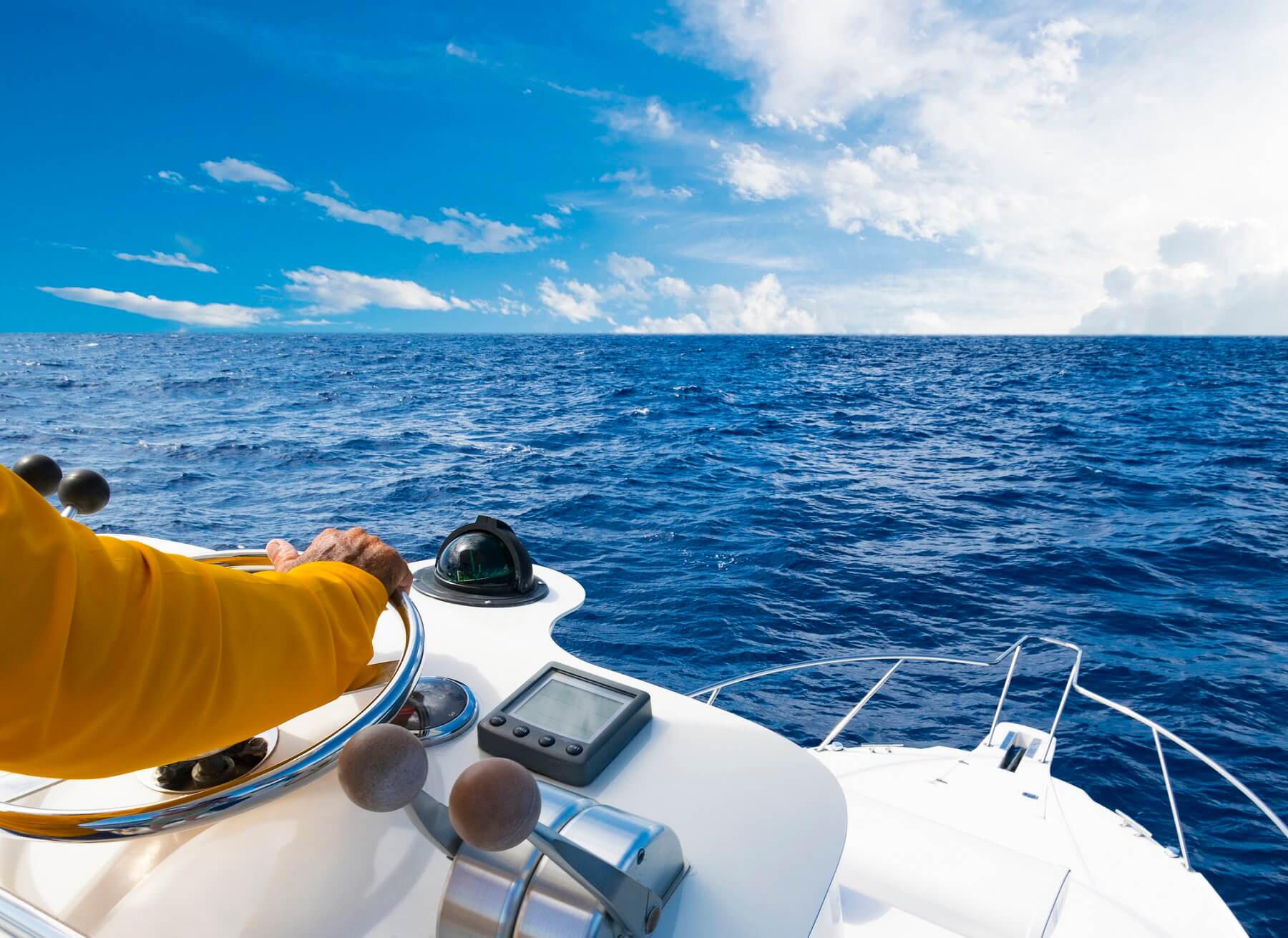 Hand of captain on steering wheel of motor boat in the blue ocean on fishing trip