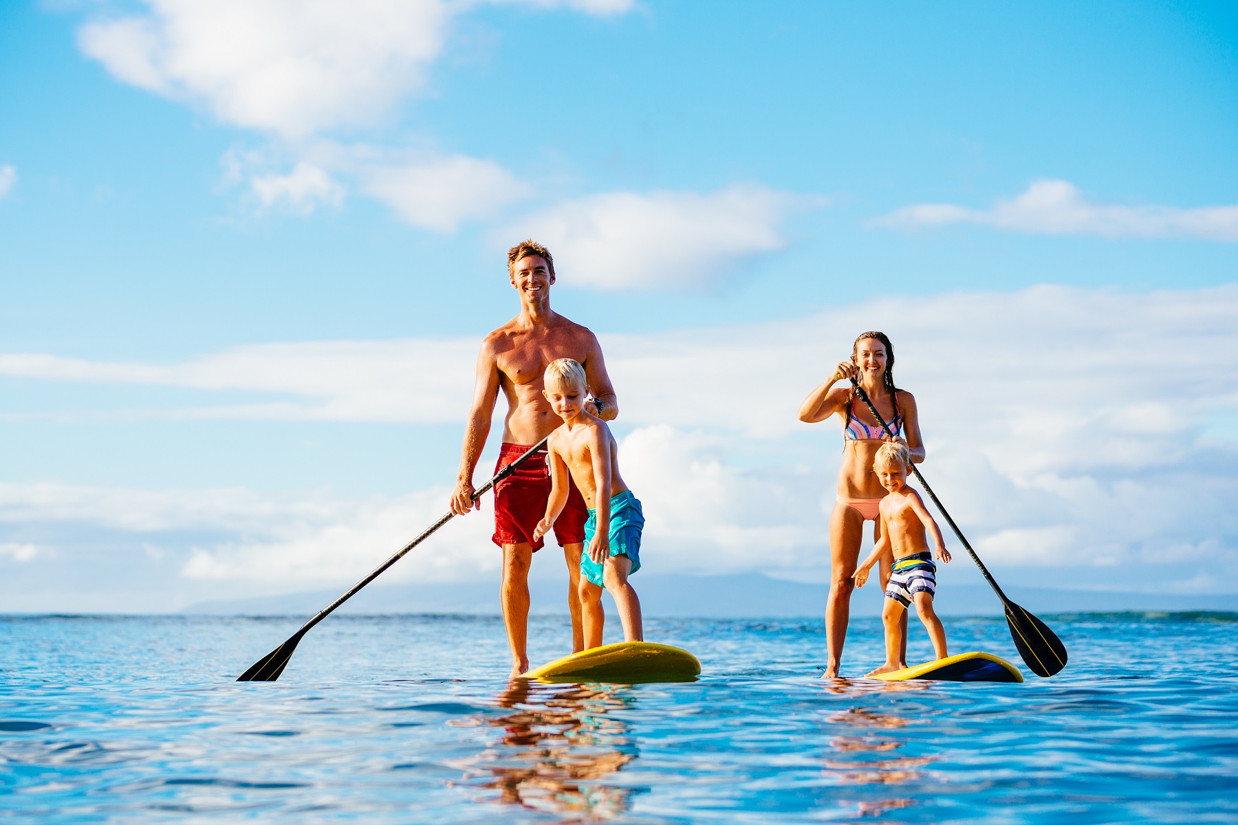 Family Having Fun Stand Up Paddling Together in the Ocean on Beautiful Sunny Morning